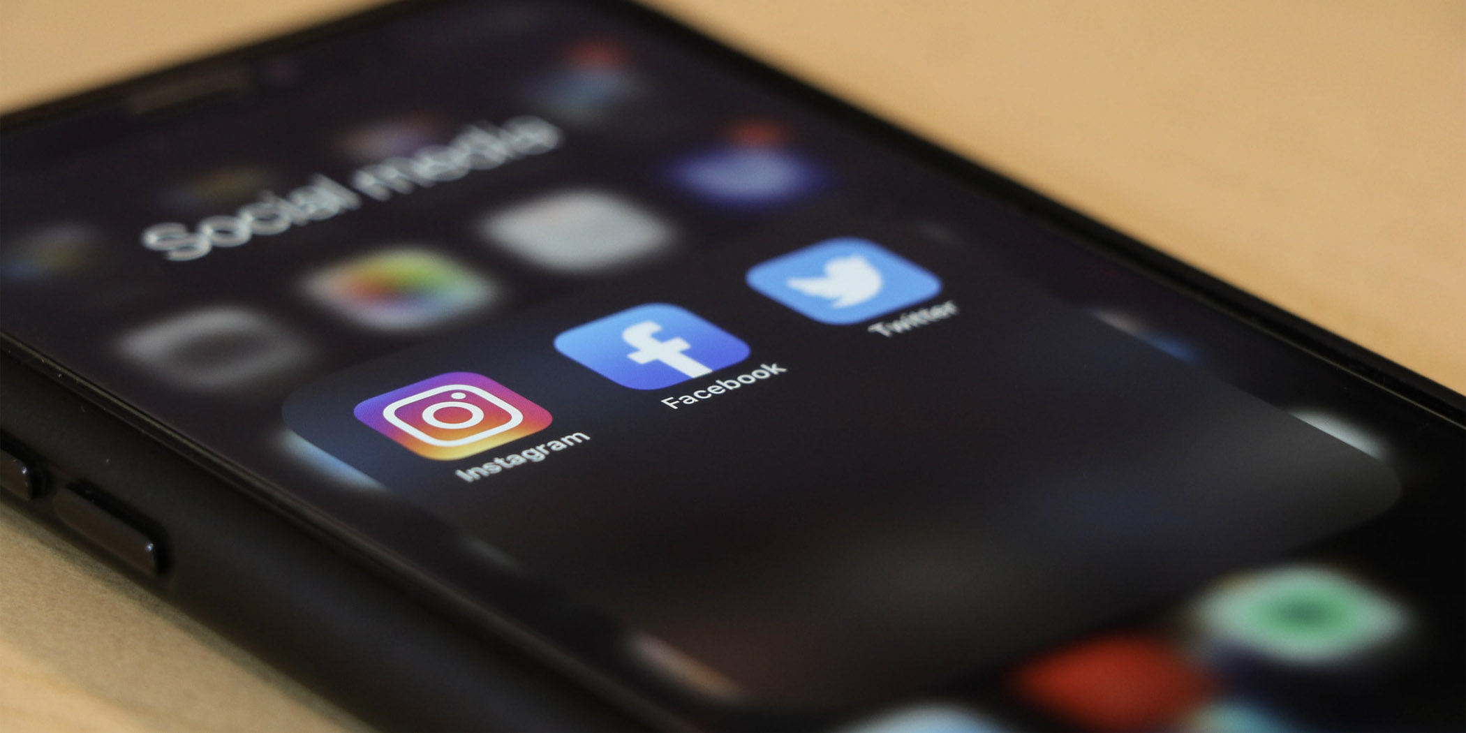 Image of an iPhone showing social media apps Instagram, Facebook, and Twitter