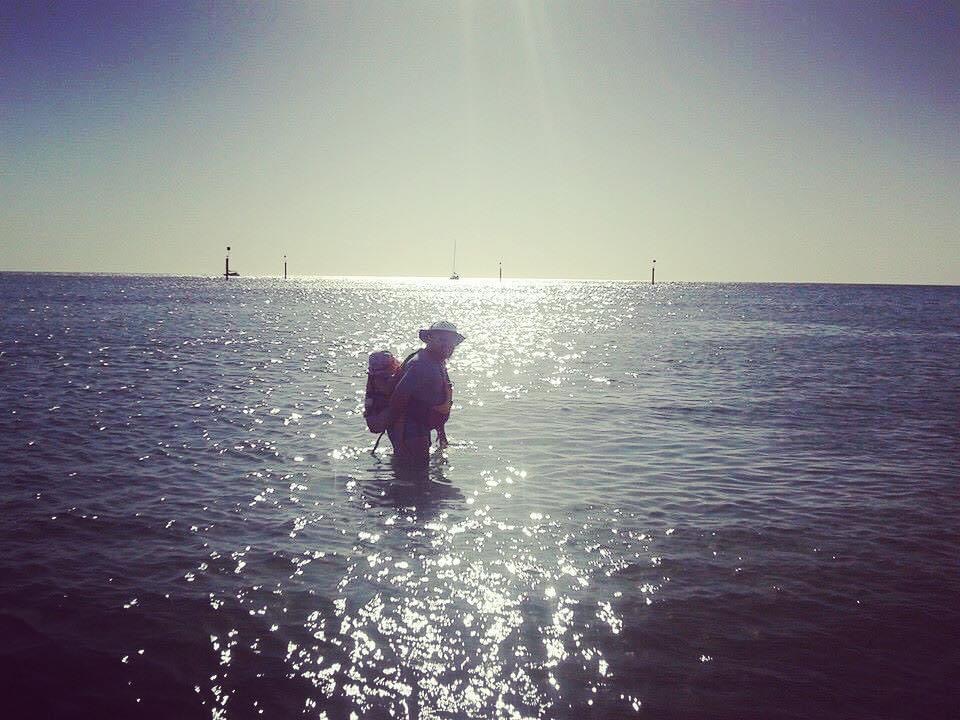 ayne carries his daughter on his back in the open ocean in South Australia.